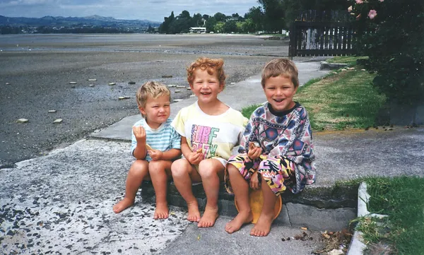 Sam, Edwin and Ben O'Dea young sitting on step by the beach
