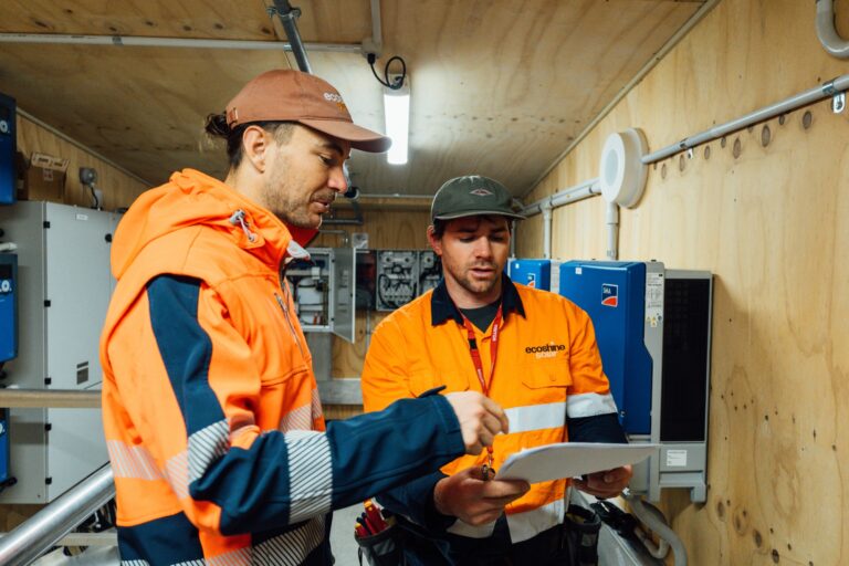 Eco Shine Solar technicians reviewing a system health report in an inverter room