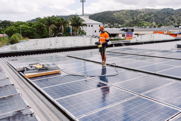 Technician guiding a robotic solar panel clean on a commercial building roof